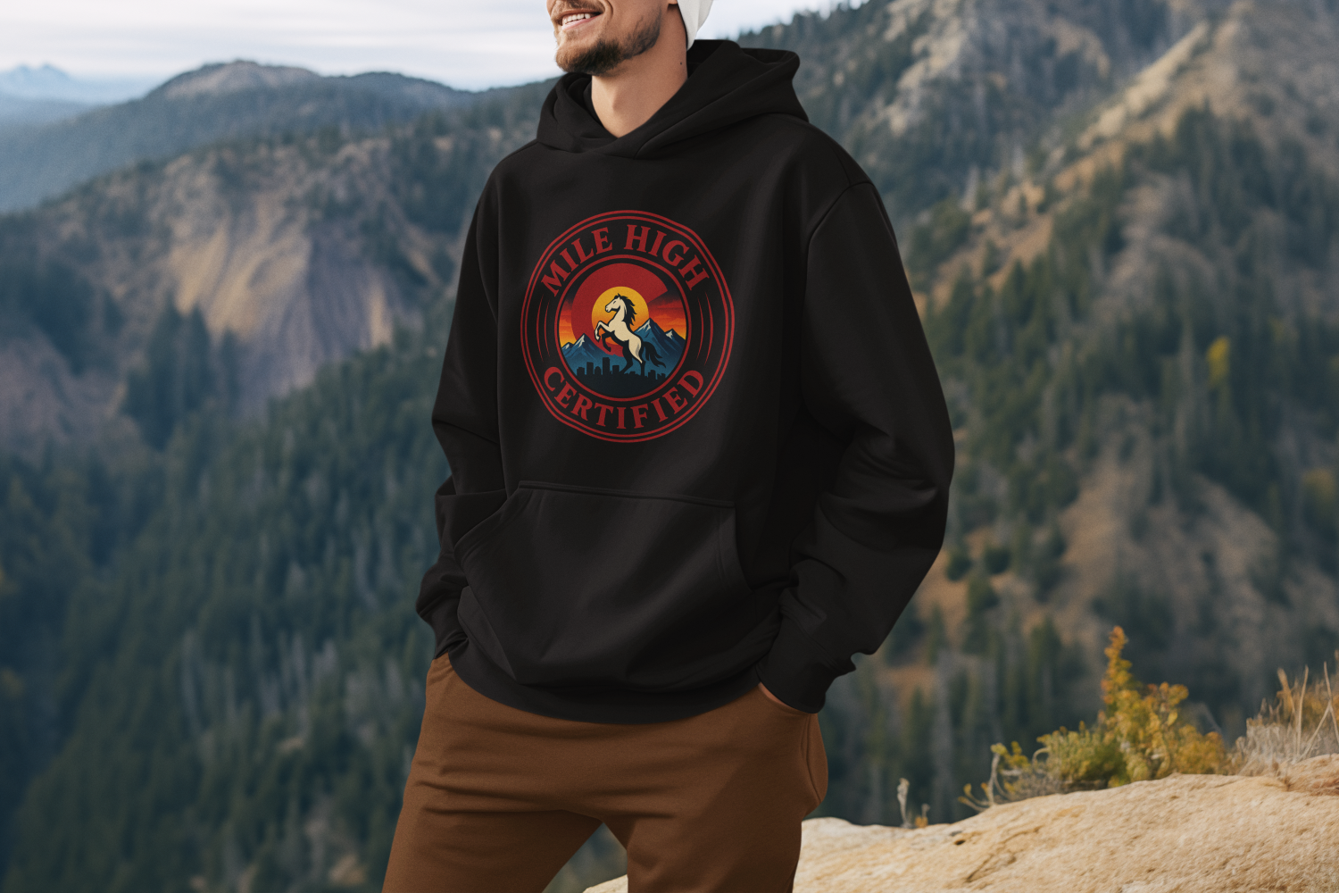 Person wearing a black hoodie with a logo in a mountainous landscape